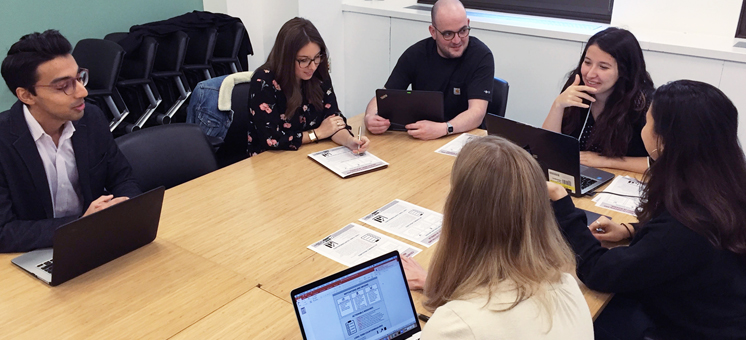 A dynamic group of students huddle in intense discussion, mapping out strategies during a high-stakes CGA practicum session.