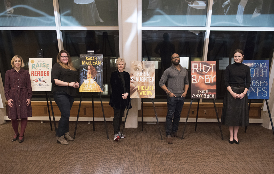 Authors Pamela Paul, Sarah MacLean, Karin Slaughter, Tochi Onyebuchi, and Veronica Roth pose in front of posters of their published book covers.