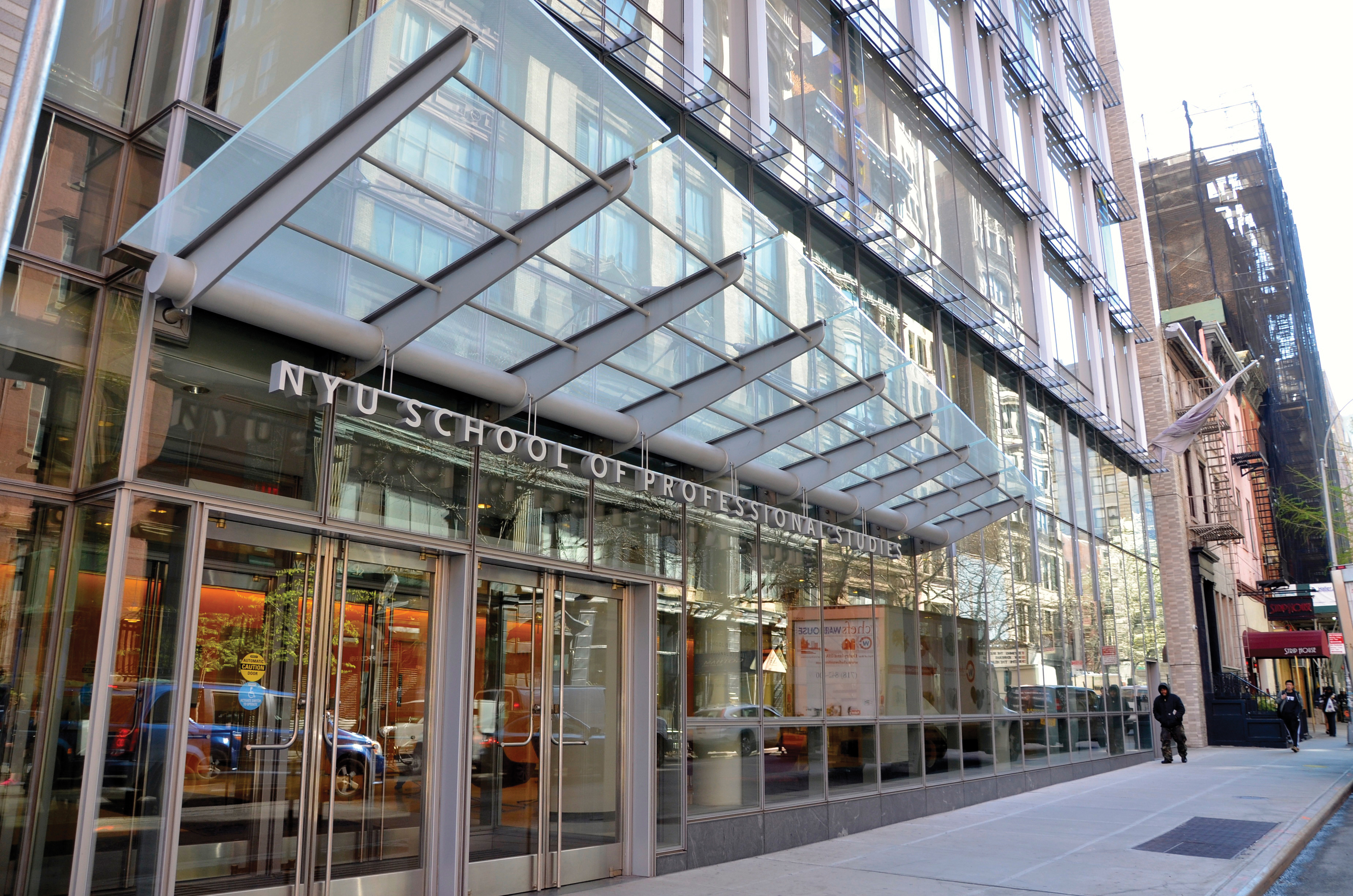 A modern glass-fronted building with the sign 'NYU School of Professional Studies' above the entrance.