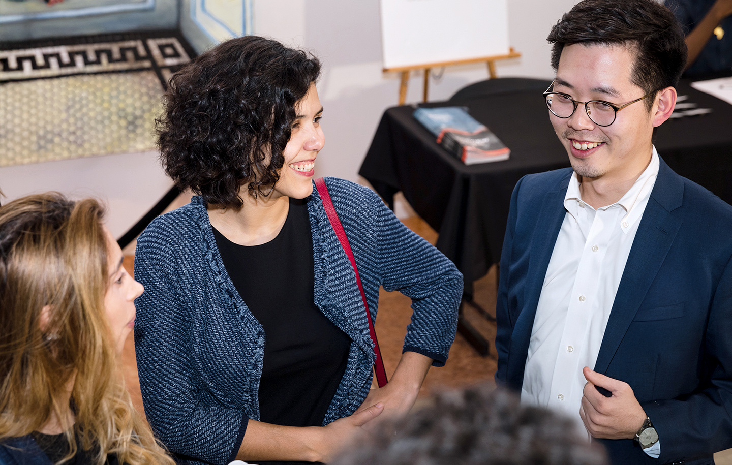Three NYU SPS alumni stand in a semi-circle and mingle during a university event