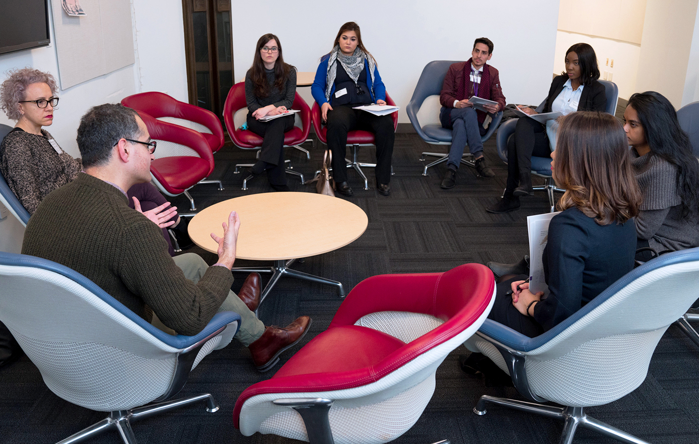 Eight NYU SPS alumni gather in a conference room to discuss NYU Alumni Clubs and Networks